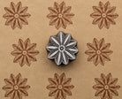 Hand-carved wooden flower printing block shown with repeated brown floral impressions on handmade tan paper.