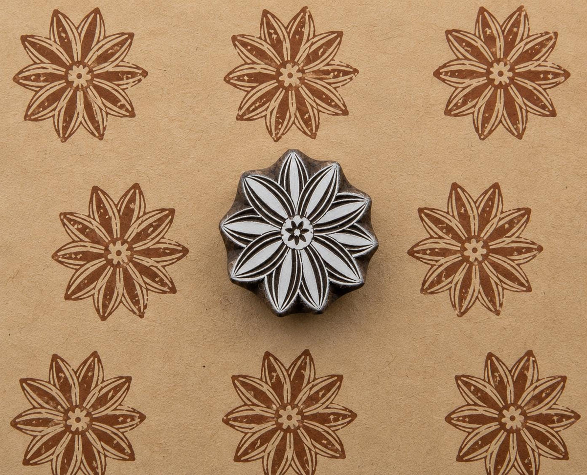Hand-carved wooden flower printing block shown with repeated brown floral impressions on handmade tan paper.