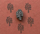Hand carved wooden Berry Tree stamp shown with repeated dark botanical tree impressions on textured terracotta handmade paper.
