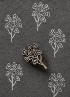 Hand carved heart leaf botanical wood printing block with white repeated impressions on dark handmade paper