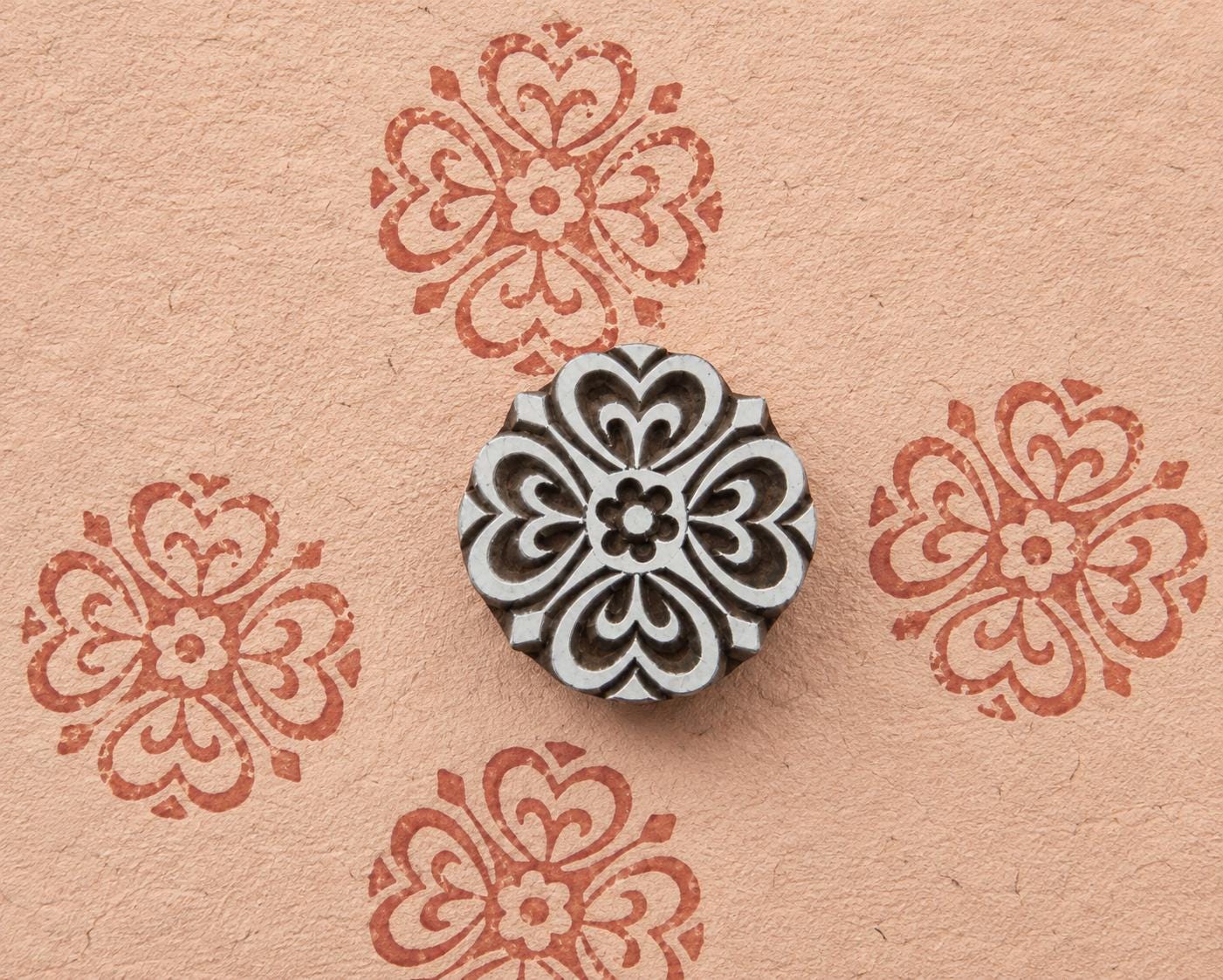 Six petal geometric wooden stamp with a symmetrical ornamental design shown on handmade paper.