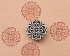 Six petal geometric wooden stamp with a symmetrical ornamental design shown on handmade paper.