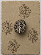 Hand carved wooden winter tree printing block with repeated tree impressions on handmade paper
