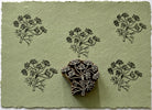 Hand carved botanical sprig wooden printing block with repeated wildflower impressions on handmade paper