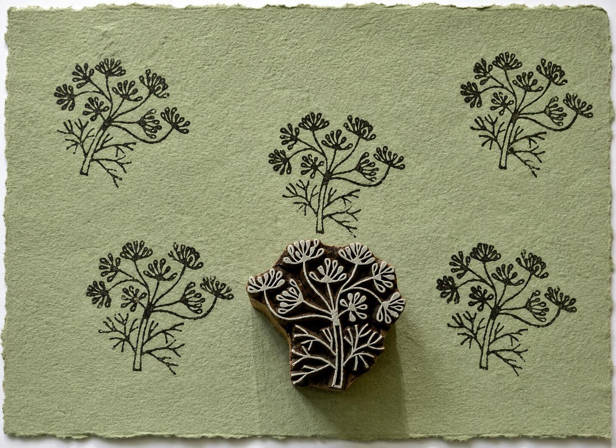 Hand carved botanical sprig wooden printing block with repeated wildflower impressions on handmade paper