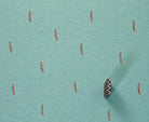 Tiny wavy vine motif repeatedly printed in rust ink on textured turquoise handmade paper with the carved wooden block shown alongside.