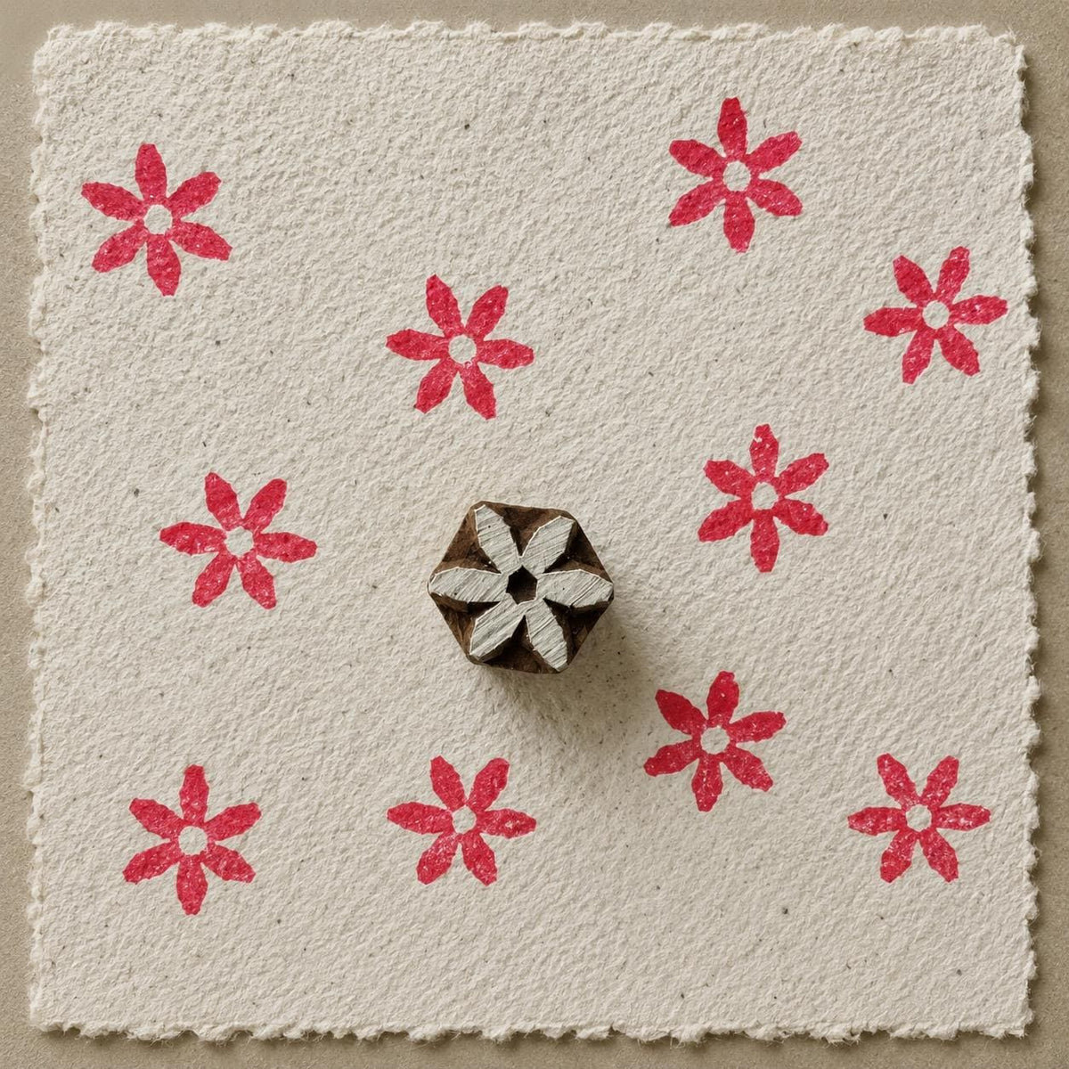 Hand carved six-petal folk flower wooden printing block with repeated red impressions on handmade paper