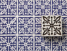 Hand carved floral tile wood stamp with four botanical flowers around a central flower, shown on handmade paper with repeated indigo impressions.