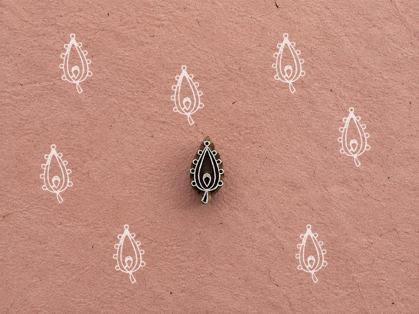 Hand carved Beaded Paisley wooden printing block with repeated paisley impressions on textured dusty pink handmade paper