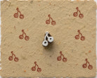 Tiny hand carved Indian wood printing block with twin cherry motif, shown with repeated red impressions on handmade paper