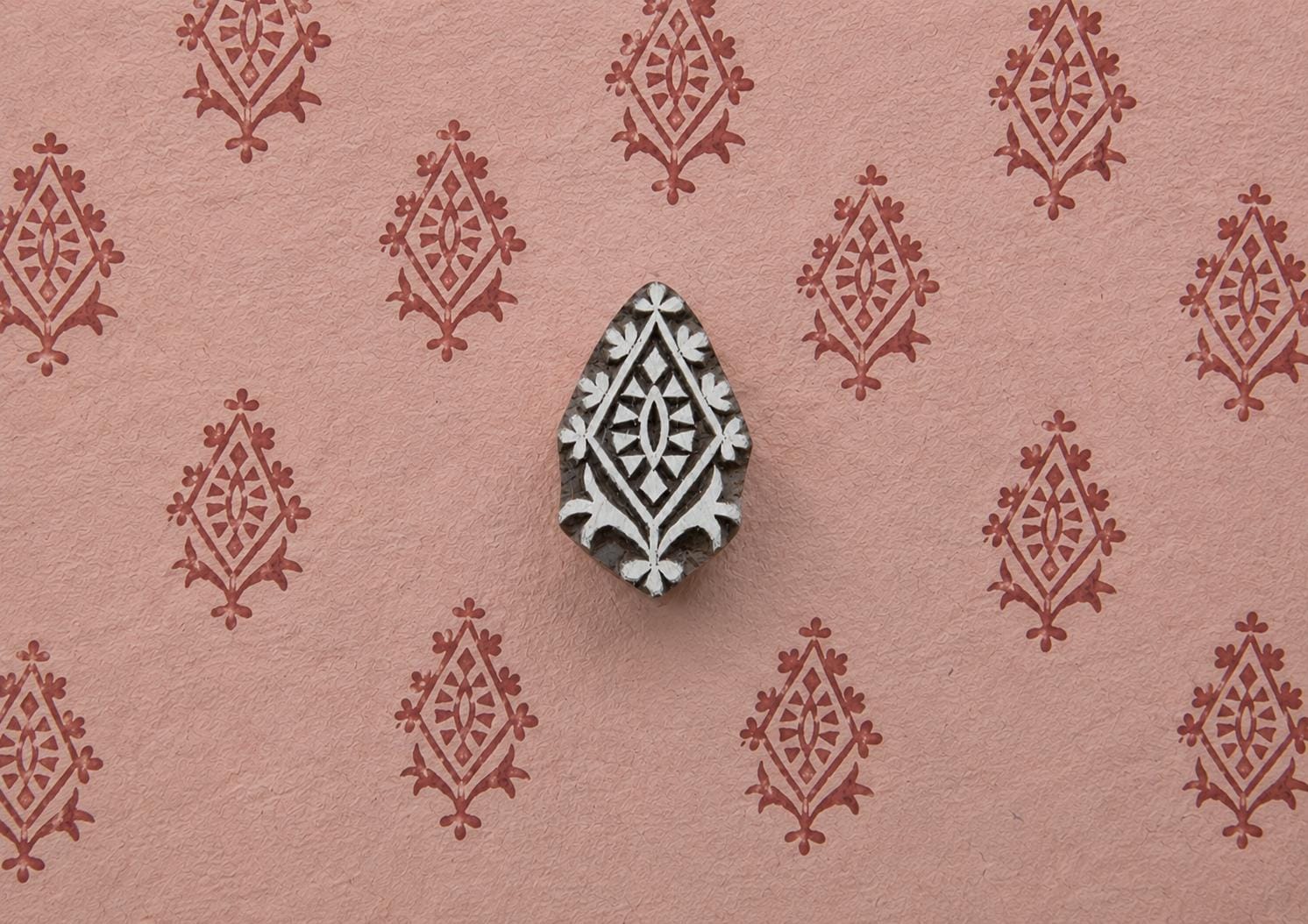Crowned Diamond hand carved Indian wood printing block creating a repeating ornamental diamond pattern on pink handmade paper