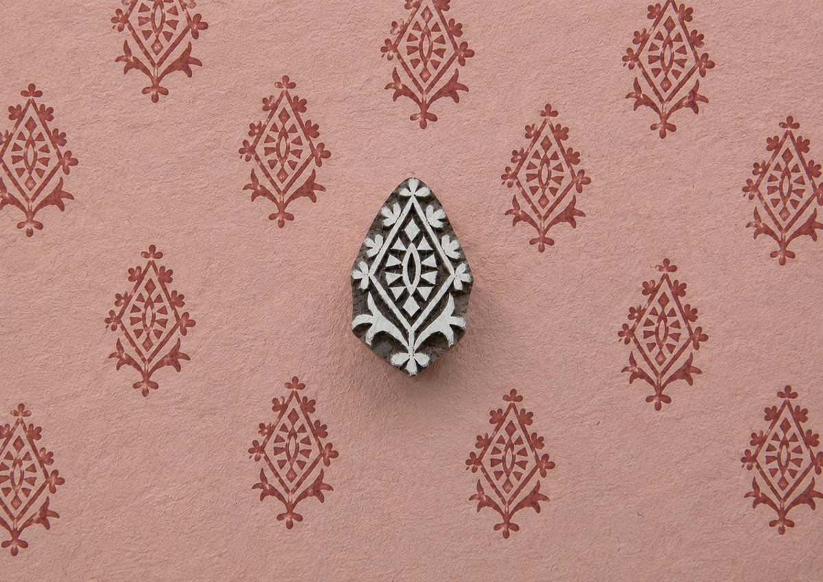 Crowned Diamond hand carved Indian wood printing block creating a repeating ornamental diamond pattern on pink handmade paper