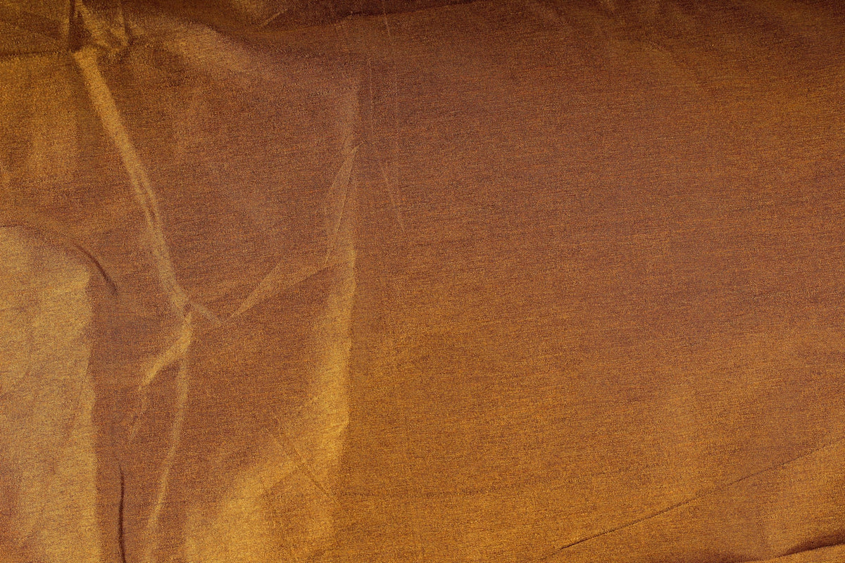 Close-up of burnt caramel poly dupioni fabric showing its fine slubbed texture and warm golden brown colour.