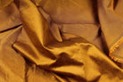 Burnt caramel faux silk dupioni fabric draped in soft folds, showing its textured surface and subtle sheen.