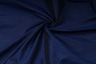 Textured royal blue dupioni look fabric arranged in folds for dressmaking and sewing