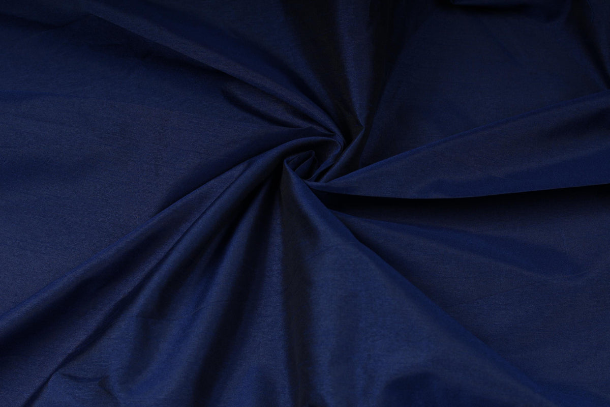 Textured royal blue dupioni look fabric arranged in folds for dressmaking and sewing
