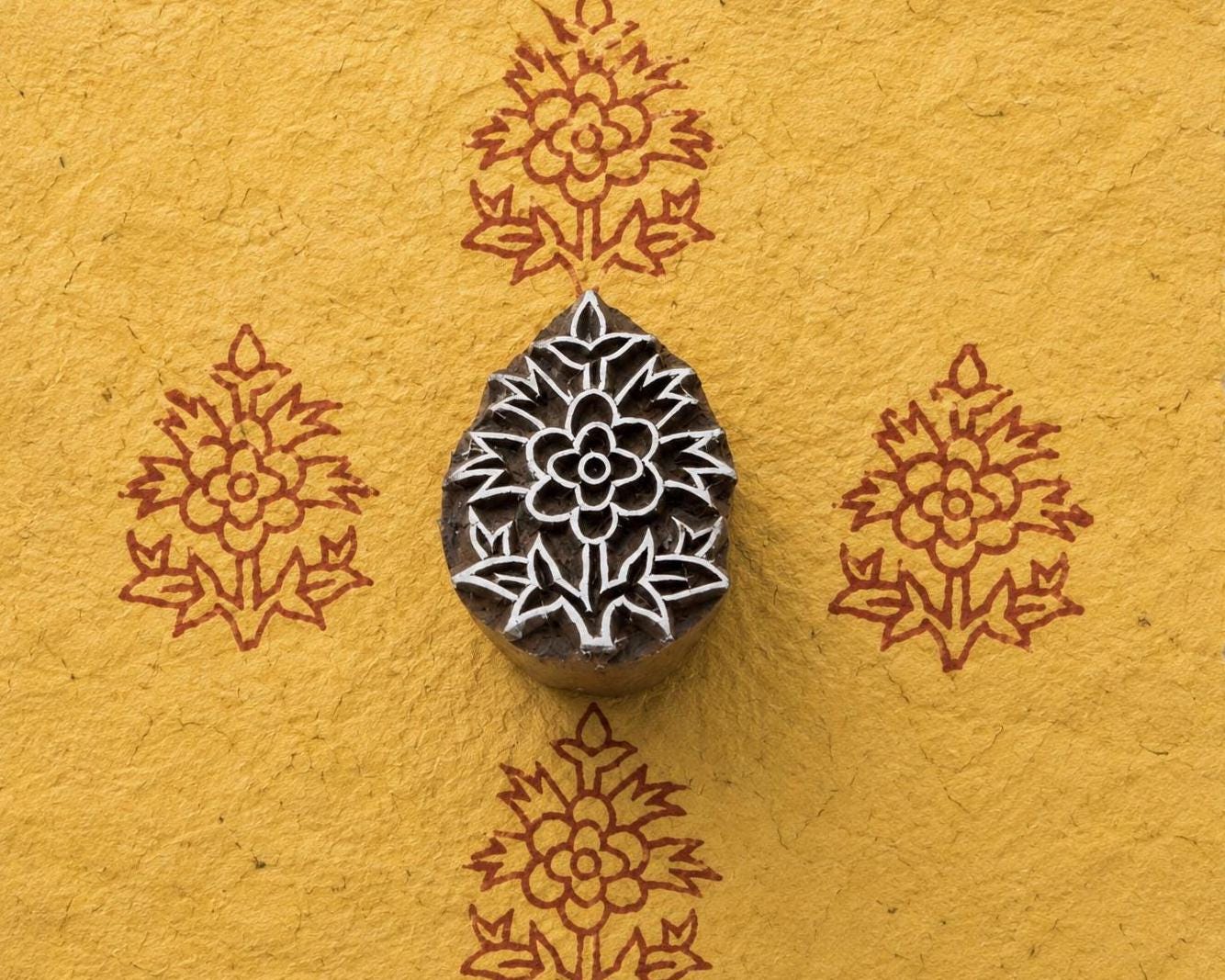 Regal Blossom hand carved Indian wood printing block shown creating a repeating blossom motif on golden handmade paper