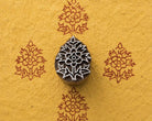 Regal Blossom hand carved Indian wood printing block shown creating a repeating blossom motif on golden handmade paper