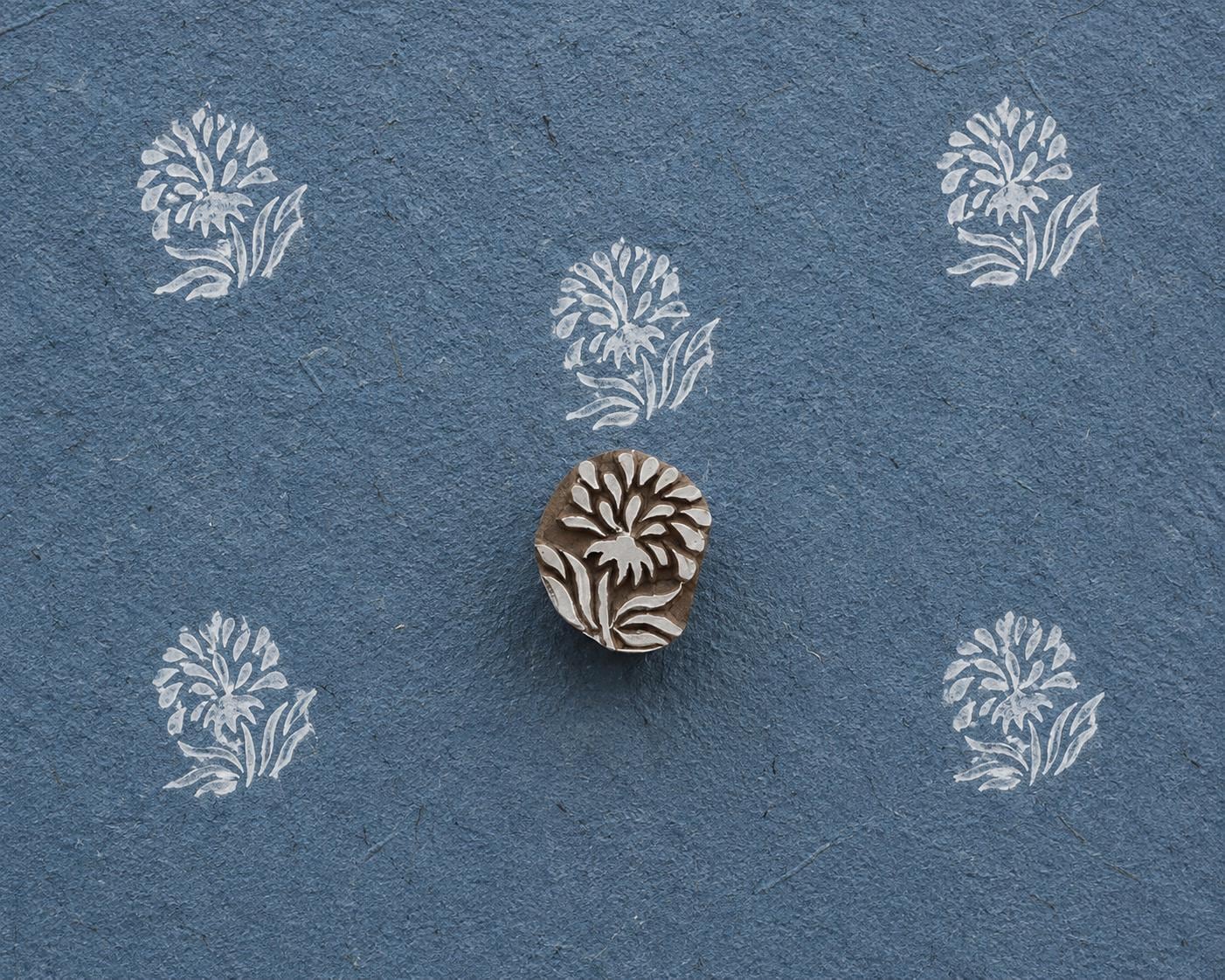 Hand-carved Wildflower Spray wooden printing block with delicate white botanical prints on textured dark blue handmade paper.