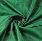 Emerald green dupioni fabric arranged in flowing folds to show its rich colour, texture and subtle sheen.