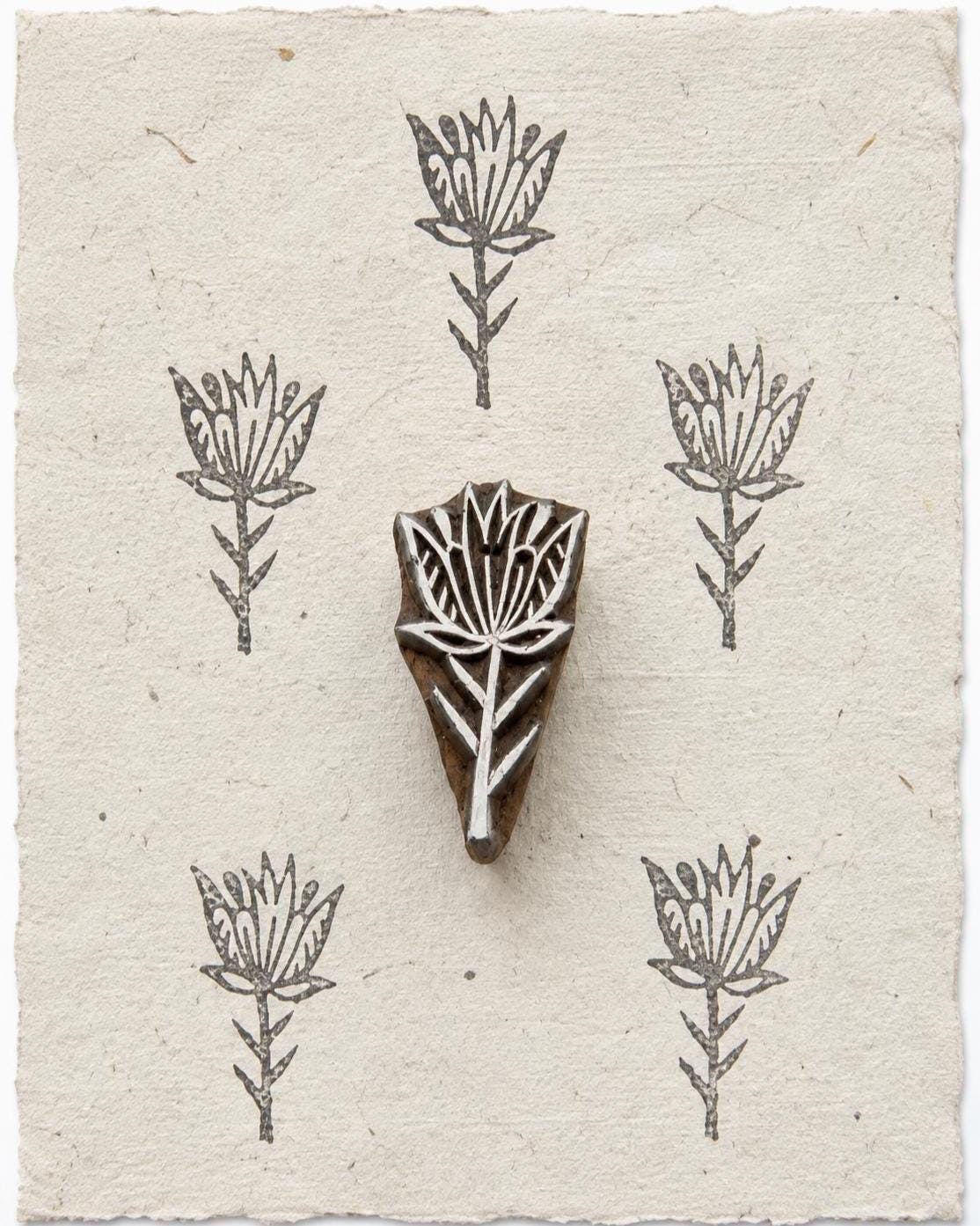 Hand carved wooden Wild Bloom botanical printing block shown with repeated flower impressions on handmade paper.