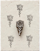 Hand carved wooden Wild Bloom botanical printing block shown with repeated flower impressions on handmade paper.