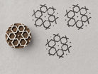 Interlocking hexagon geometric wood block stamp with repeated handmade impressions on paper