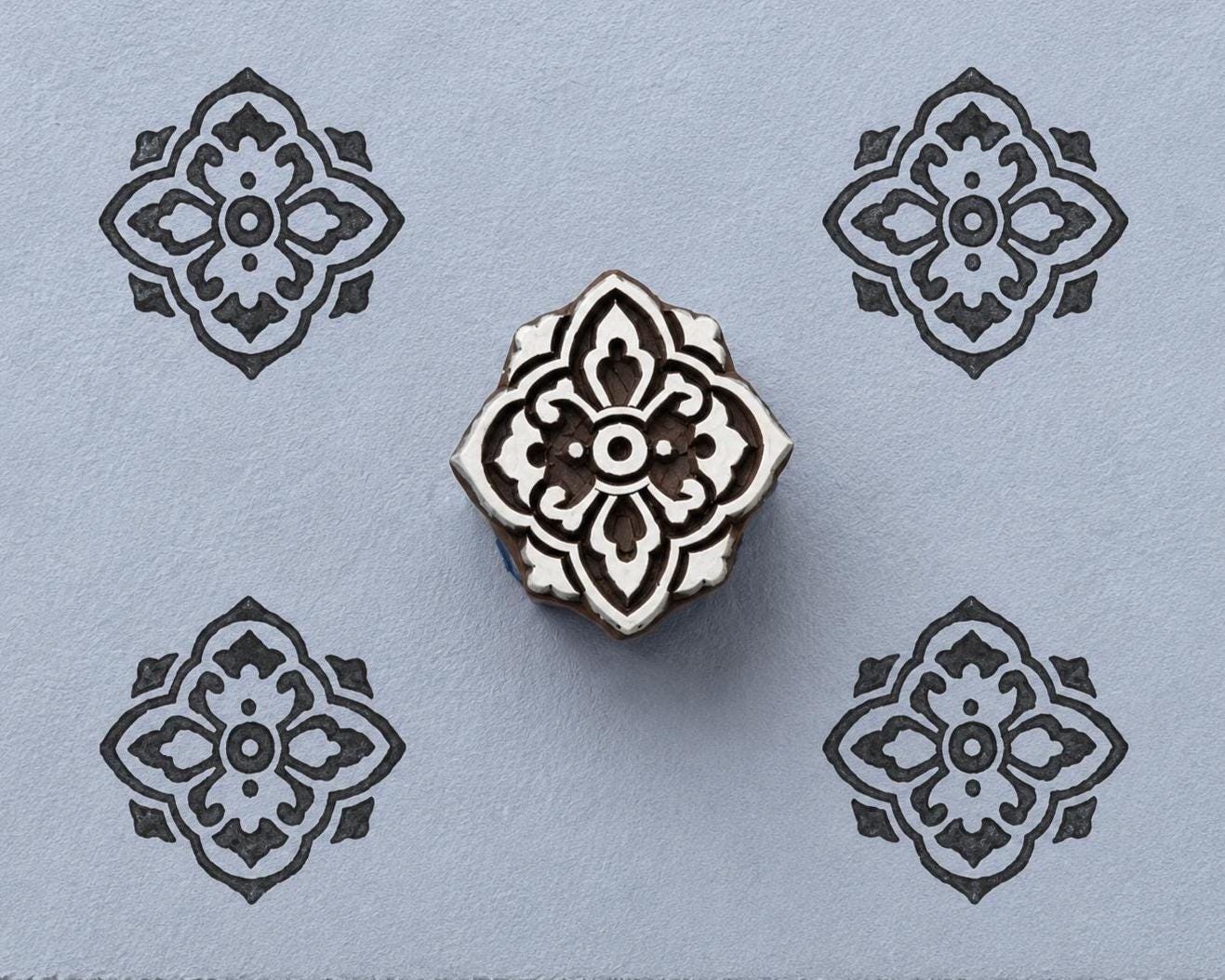 Ornamental quatrefoil wood block stamp with repeated tile pattern impressions on handmade paper