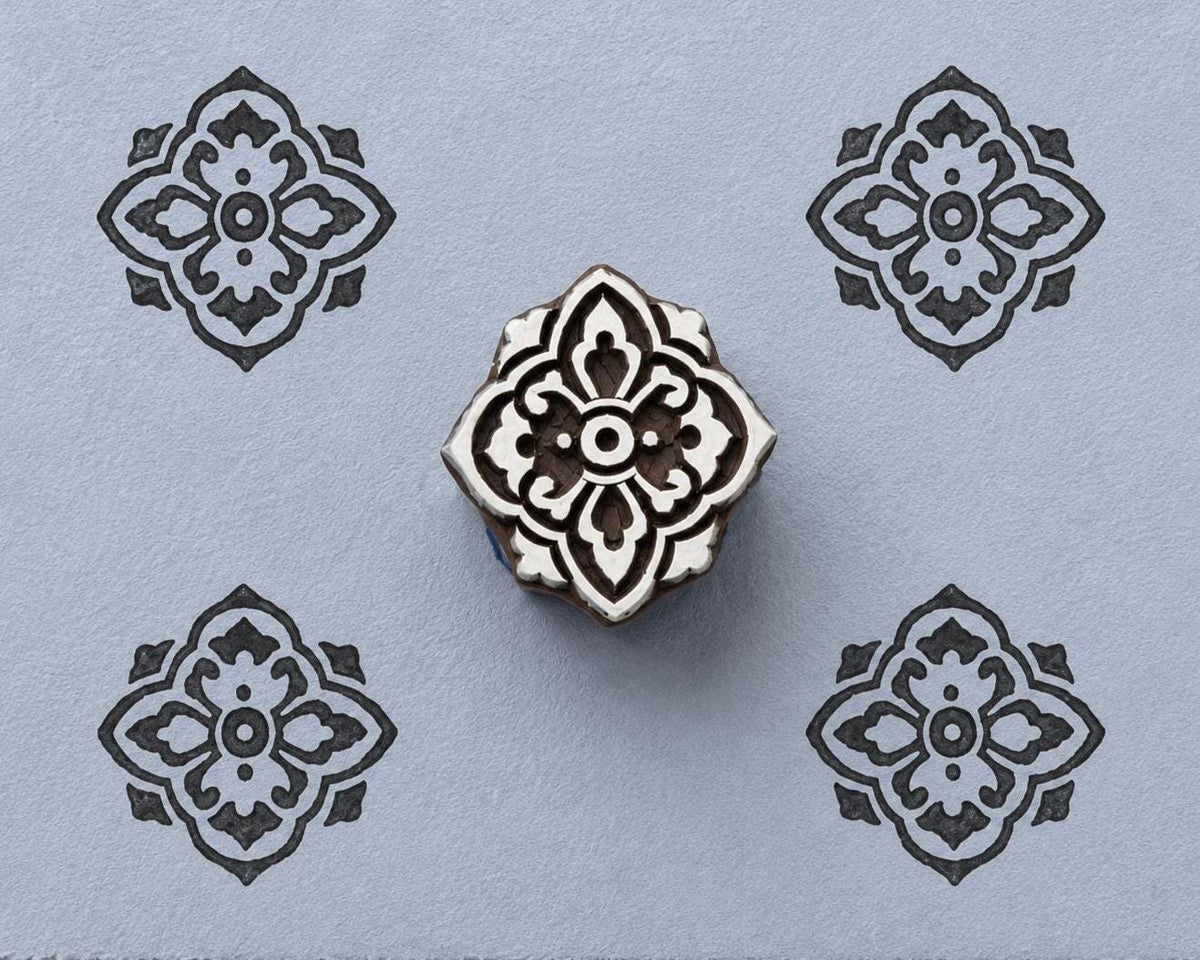Ornamental quatrefoil wood block stamp with repeated tile pattern impressions on handmade paper
