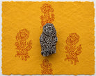 Hand carved floral bouquet wood printing block shown on golden handmade paper with repeated botanical impressions