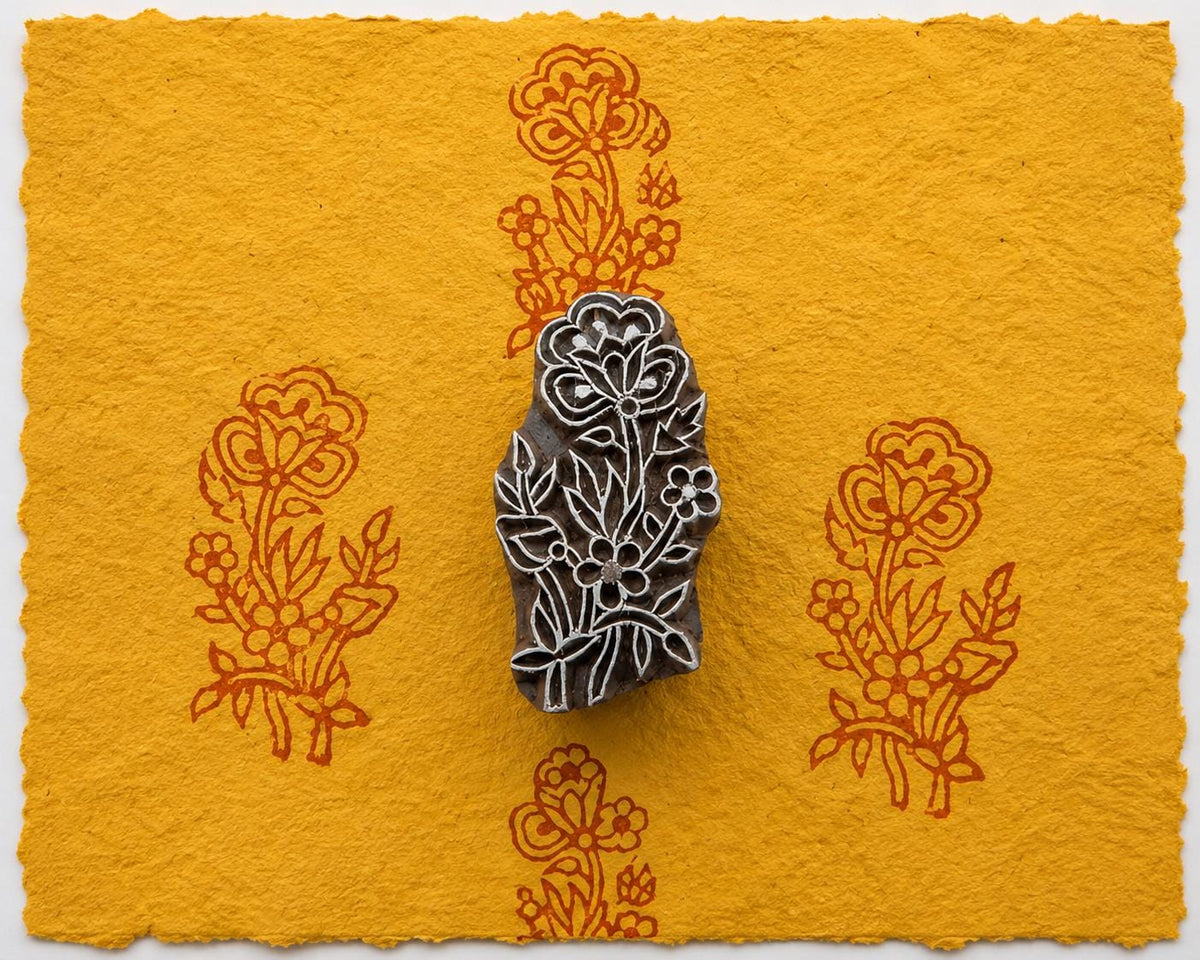 Hand carved floral bouquet wood printing block shown on golden handmade paper with repeated botanical impressions