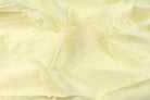 Vanilla cream faux silk fabric arranged in flowing folds to show its subtle shine and drape.