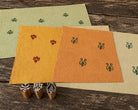 Three small hand-carved Indian motif wooden printing blocks displayed with their printed impressions on colourful handmade paper.