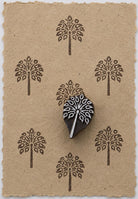 Hand carved leaf tree wooden printing block shown on handmade paper with repeated botanical impressions