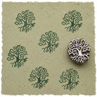 Hand carved Tree of Life wooden printing block shown with repeated green botanical impressions on handmade paper