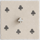 Hand carved wooden club clover printing block shown on handmade paper with six dark ink impressions in a repeating pattern.