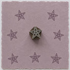 Hand carved geometric star wooden printing block with repeated star impressions on handmade paper