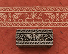 Hand carved Indian wooden printing block featuring two decorative elephants facing each other with a floral motif and geometric border bands, shown with a printed border on handmade paper.