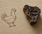 Hand-carved wooden rooster printing block shown beside its printed rooster impression on textured handmade paper