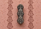 Hand carved wooden Floral Totem printing block with a repeating floral border printed on textured pink handmade paper.