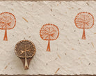 Crowned Tree hand carved wooden printing block with repeated terracotta impressions on handmade paper.