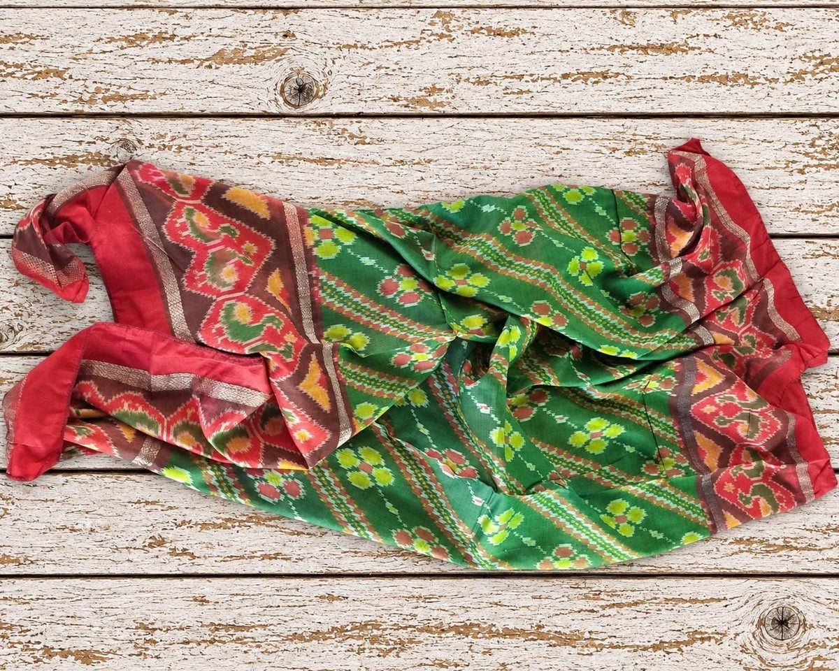 Vintage green silk sari piece loosely draped to show the flowing fabric and colourful geometric floral design