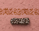 Meandering Vine Border hand carved wooden printing block with a flowing floral vine impression on handmade pink paper.