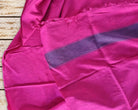 Fuchsia pink silk textile with purple striped border and fringed edge, shown draped to reveal its sheen and texture