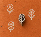 Small hand-carved Daisy Flower wooden printing block with white flower prints on textured burnt orange handmade paper.