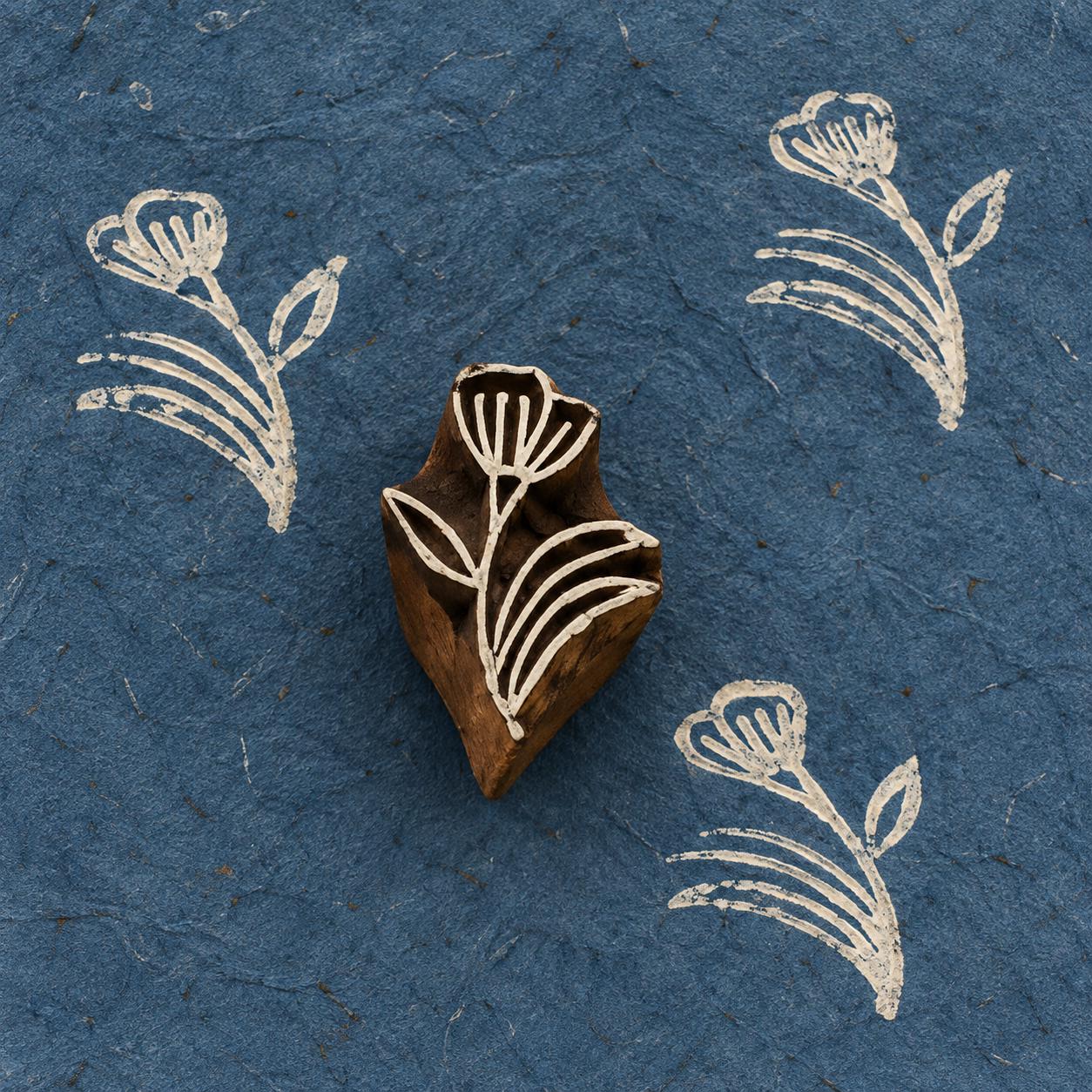 Hand-carved Meadow Bloom wooden printing block with white floral prints on textured dark blue handmade paper.