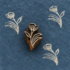 Hand-carved Meadow Bloom wooden printing block with white floral prints on textured dark blue handmade paper.