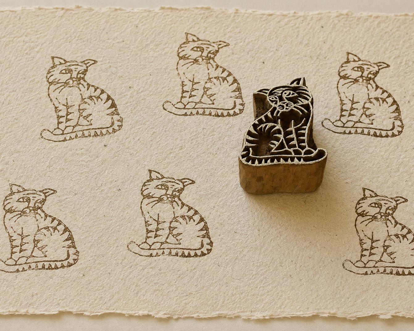 Hand-carved wooden tiger printing block surrounded by repeated tiger prints on textured handmade paper.