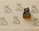 Hand-carved wooden tiger printing block surrounded by repeated tiger prints on textured handmade paper.
