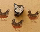Hand-carved wooden rooster printing block surrounded by three repeated brown rooster prints on textured handmade paper.